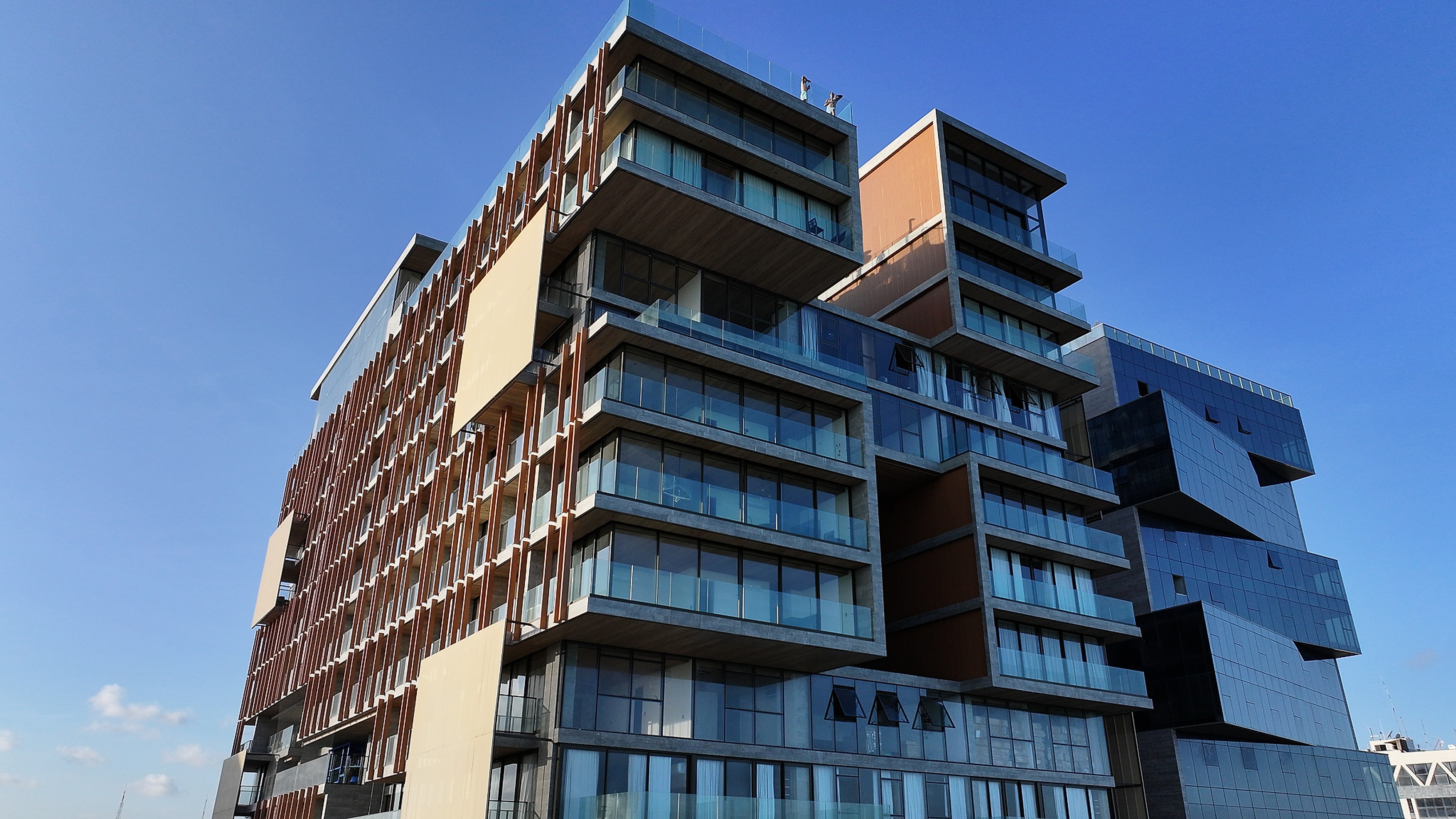 Fachada de edifício residencial com varandas de vidro e madeira
